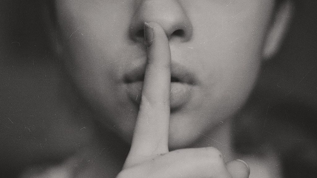 Eine Frau legt den Finger an die Lippen