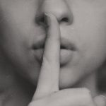 Eine Frau legt den Finger an die Lippen