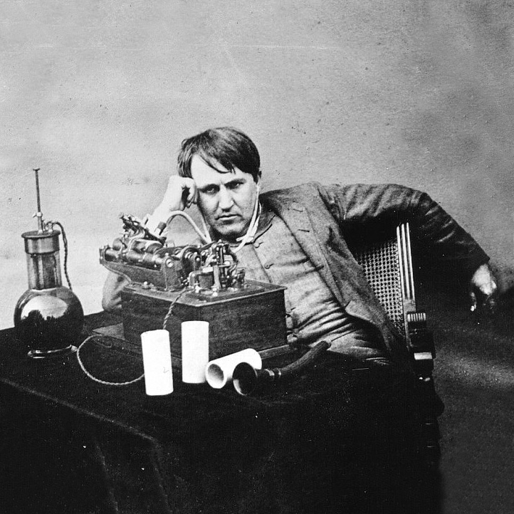 Thomas Edison sitzt vor einer frühen Version seines Phonographen, er wirkt konzentriert. 1888