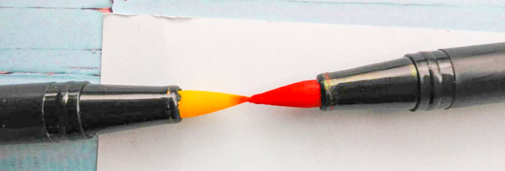 Zwei Stiftspitzen von zwei Pinselstiften, die gegeneinander gedrückt werden, um einen Gradient aus Farben zu erstellen. Die linke Spitze hat eine gelbe Farbe und die rechte Spitze eine rote. Einstiegsmaterialien Porträtzeichnungen 
