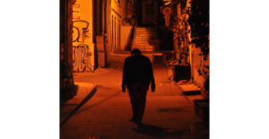 Ein Mann läuft eine nächtliche Gasse mit Graffitti an den Wänden hinab