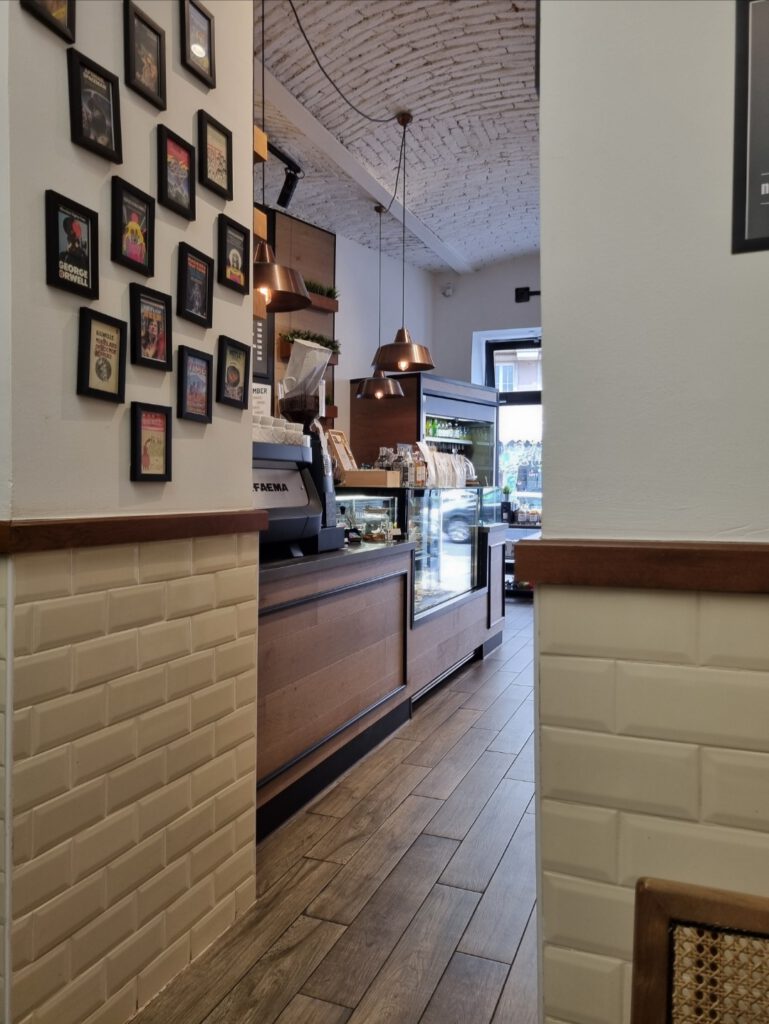 Neyse Café mit Blick auf die Theke. An der Wand hängen verschiedene Karten in Bilderrahmen.