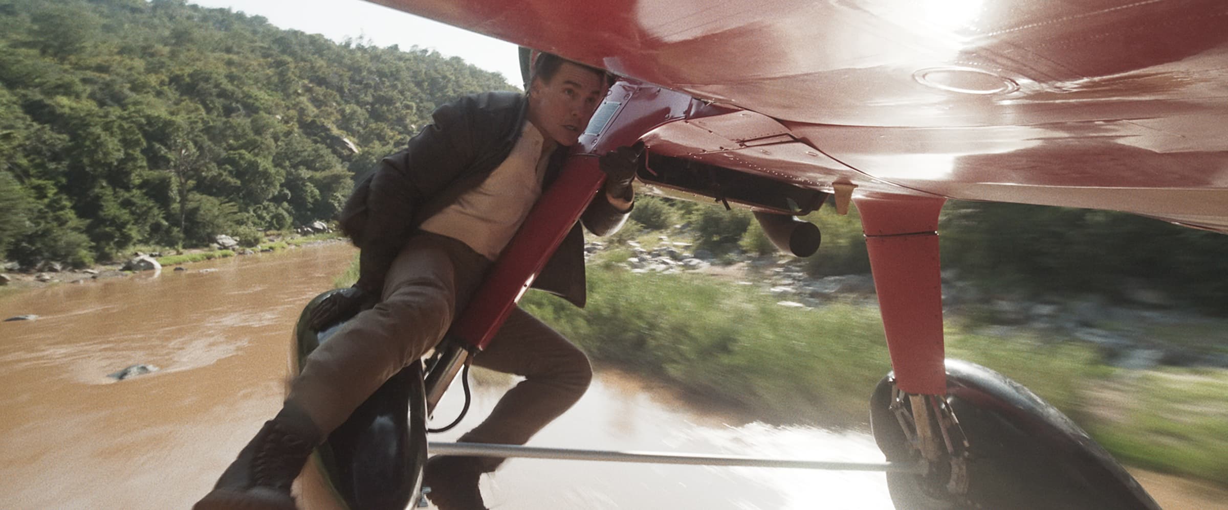 Ethan Hunt sitzt auf Fahrwerk von fliegendem Kleinflugzeug über Fluss