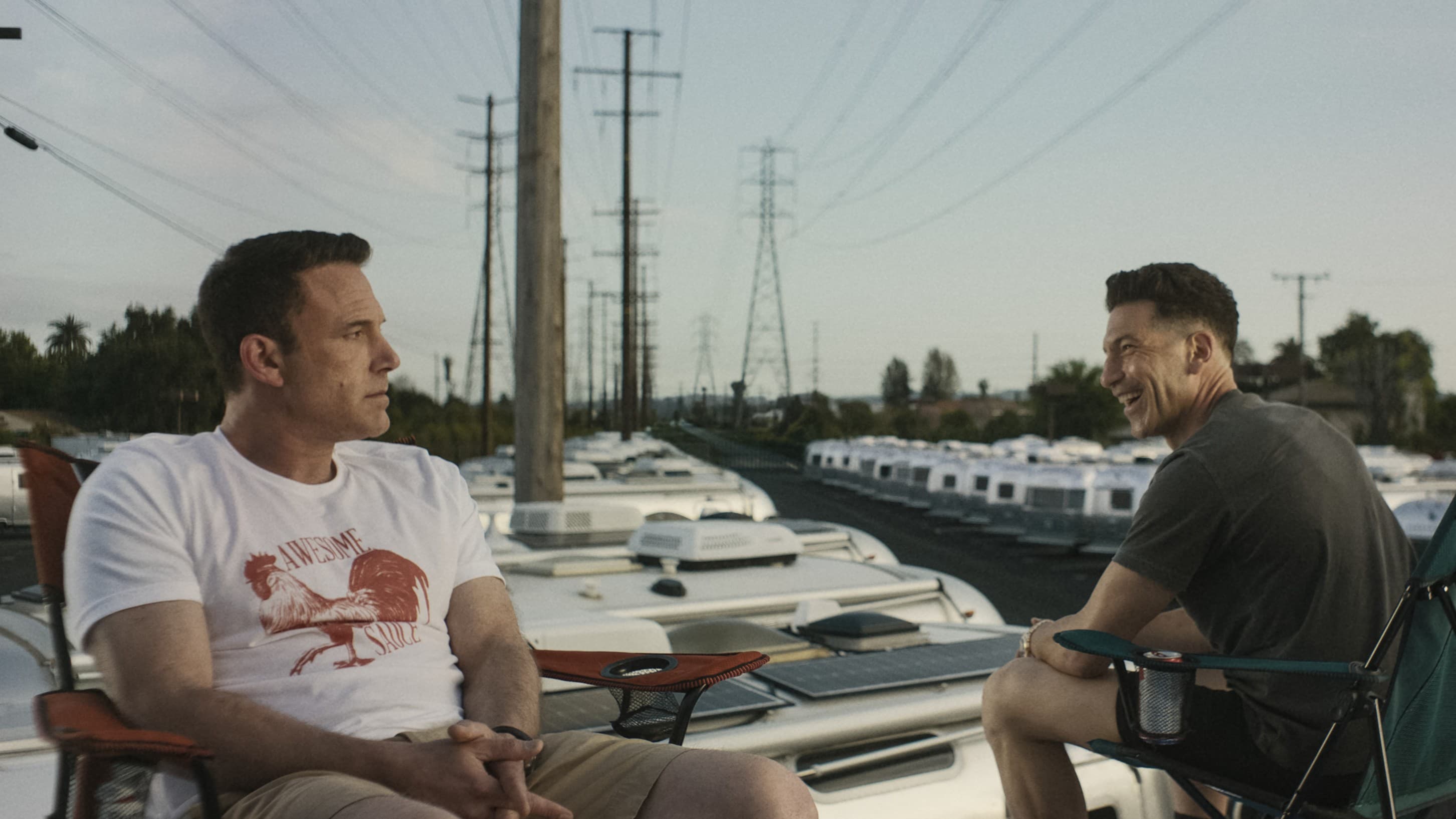 Zwei Männer sitzen in Klappstühlen auf dem Dach eines Wohnwagens und haben Spaß